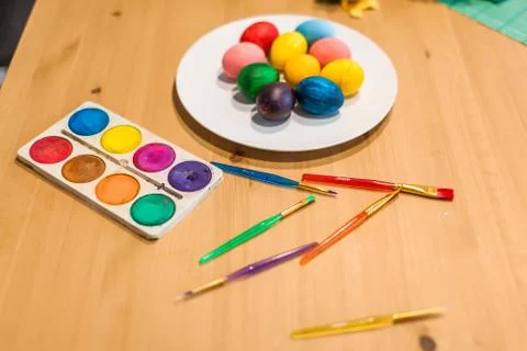Easter colored eggs and brushes on the table at home Stock Photos