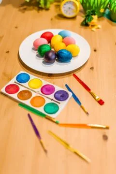 Easter colored eggs and brushes on the table at home Stock Photos