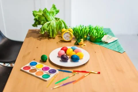 Easter colored eggs and brushes on the table at home Stock Photos