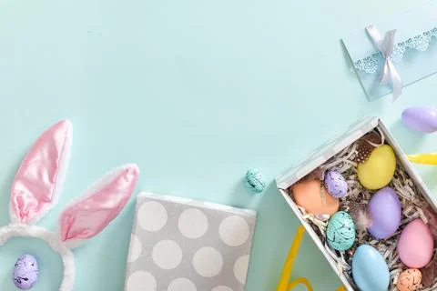 Easter colored eggs are in a box next to rabbit ears and a blue envelope. Foto stock