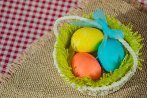 Easter colored eggs in a basket on a canvas napkin and checkered tablecloth. 写真素材