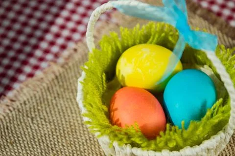 Easter colored eggs in a basket on a canvas napkin and checkered tablecloth. 写真素材