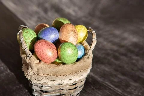 Easter colored eggs in a basket on dark wooden background. Stock Photos