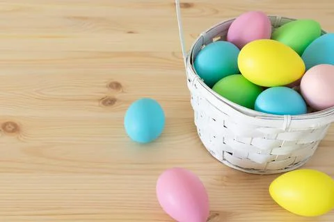 Easter colored eggs in the basket on the table. Stock Photos