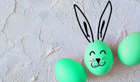 Easter colored eggs with bunny ears on light textured background. Stock Photos