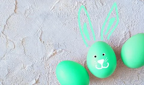 Easter colored eggs with bunny ears on light textured background. Stock Photos
