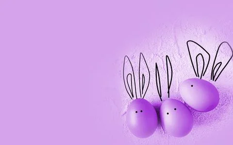 Easter colored eggs with bunny ears on purple background. Stock Photos