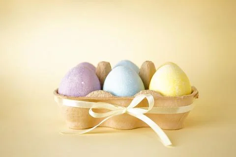 Easter colored eggs in egg tray on a yellow background. Stock Photos