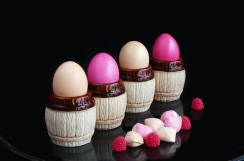 Easter colored eggs in the stands, and sweets on a black background Stockfoto's