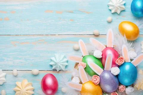 Easter colored eggs with sweets and rabbit ears. Flat lay. Easter festive bac Stock Photos