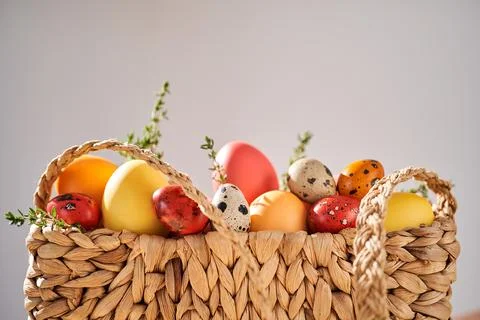 Easter colored eggs in a wicker bag. Easter composition. Stock Photos