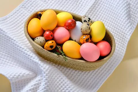 Easter colored eggs in a wicker basket. Easter composition. Stock Photos