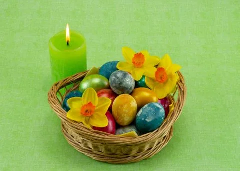 Easter, colored painted eggs in a wicker basket with moss, daffodils and cand Stock Photos