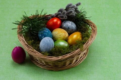 Easter, colored painted eggs in a wicker basket with moss and candle Stock Photos