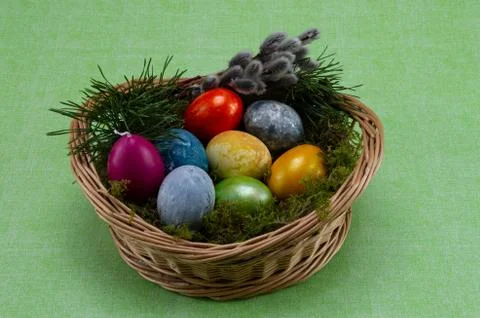 Easter, colored painted eggs in a wicker basket with moss and candle Stock Photos