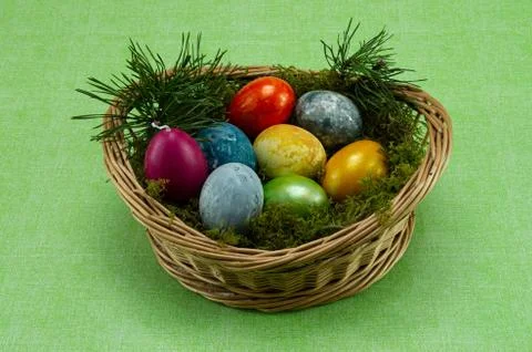 Easter, colored painted eggs in a wicker basket with moss and candle Stock-Fotos