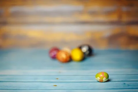 Easter colored painted small egg on blue and brown blurry wooden background Stock Photos