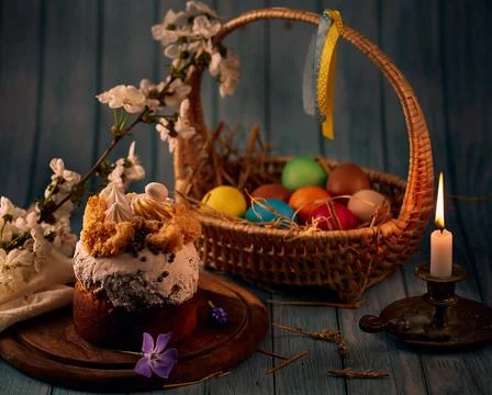 Easter compositio. Easter cake, a basket with colored eggs, a bronze candlest Stock Photos