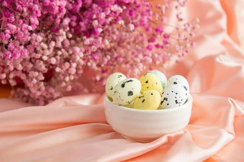 Easter composition on a background of pink satin quail eggs in a white cerami Stock Photos