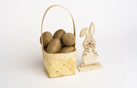Easter composition. Basket with eggs wrapped in jute twine. Wooden bunny on.. Foto stock