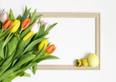 Easter composition with a bouquet of tulips, frame and yellow eggs Stock Photos