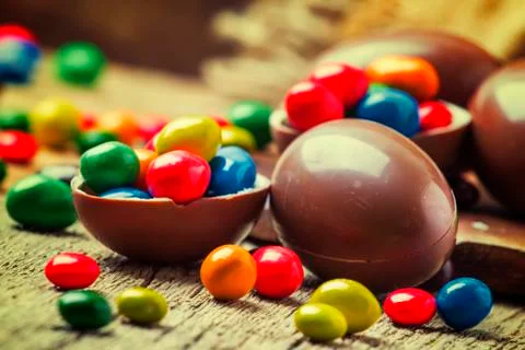 Easter composition with chocolate eggs and colorful candy, vintage wooden bac Stock Photos