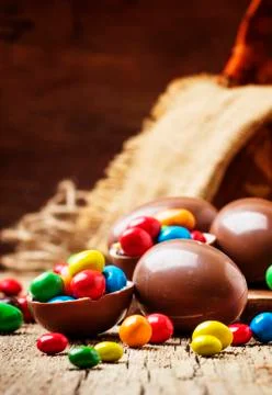 Easter composition with chocolate eggs and colorful candy, vintage wooden bac Stock Photos