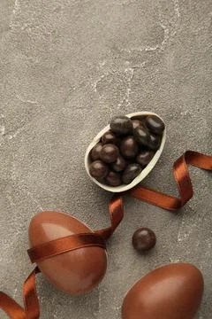 Easter composition with chocolate eggs and brown ribbon on grey background Stock Photos