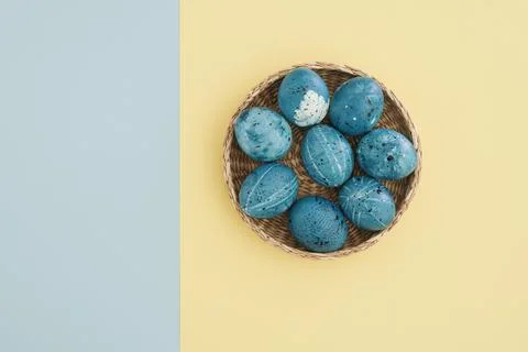 Easter composition with colored eggs in a basket on a yellow-blue background Stock Photos