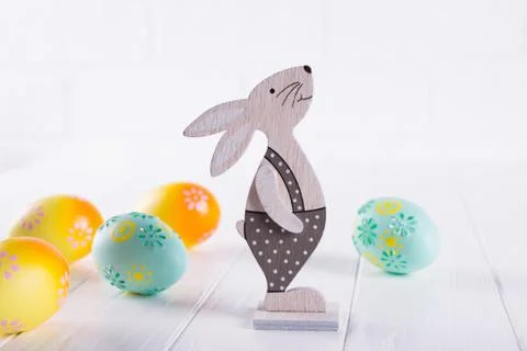 Easter composition with colorful easter eggs, decorative wooden bunny. Stock Photos