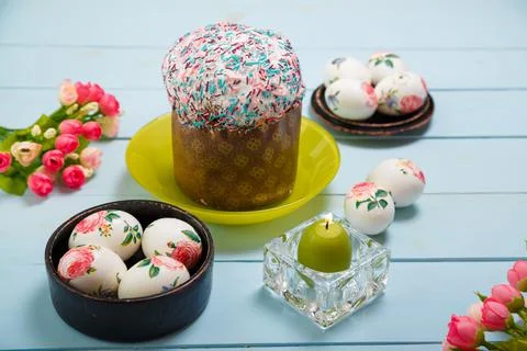 Easter composition with decorated eggs, flowers, burning candle, Easter cake Stock Photos