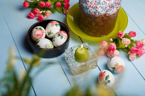 Easter composition with decorated eggs, flowers, burning candle and cake Stock Photos