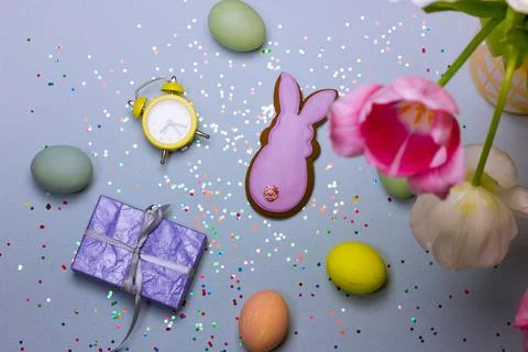 Easter composition - dyed multicolored eggs, retro alarm clock, gift box, bunny Stock-Fotos