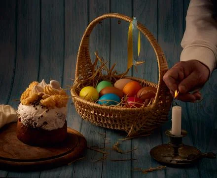 Easter composition. Easter cake, a basket with colored eggs, a bronze candle Stock Photos