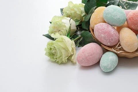 Easter composition. Easter colorful eggs in a wicker basket and roses on a wh Stock Photos