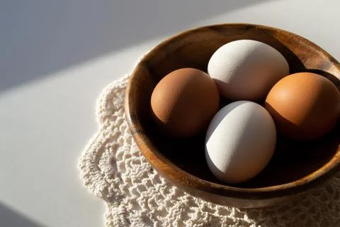 Easter composition. Easter eggs in a wooden plate in the sunlight on a white Stock Photos