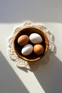 Easter composition. Easter eggs in a wooden plate in the sunlight on a white Stock Photos