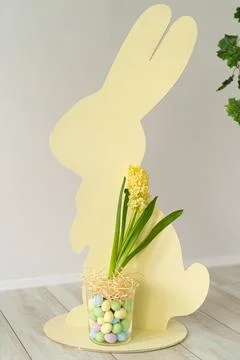 Easter composition. Easter wooden bunny, colorful dyed eggs in glass vase with Stock Photos