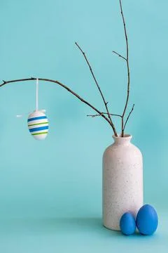 Easter composition with egg hanging on dry branch placed in vase Stock Photos