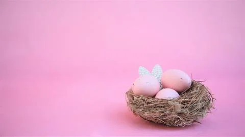 Easter composition with eggs and rabbit ears made of small pearls on pink pas Stock Photos