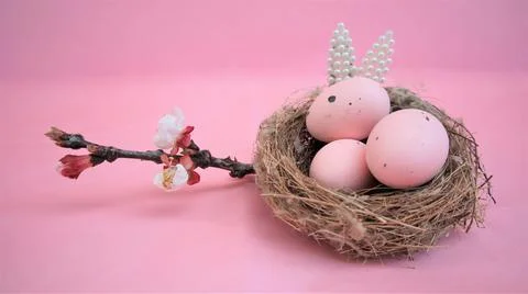 Easter composition with eggs and rabbit ears made of small pearls on pink pas Stock Photos