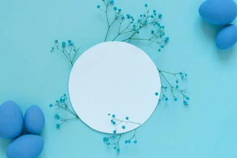 Easter composition with eggs and twigs of blue flowers around white circle frame Stock Photos