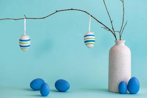 Easter composition with eggs hanging on dry branch placed in vase 库存照片