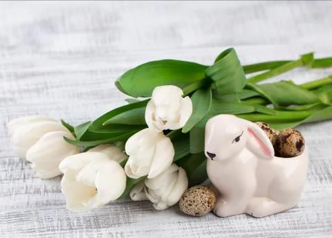 Easter composition with eggs, spring tulips and porcelain easter bunny on old 库存照片