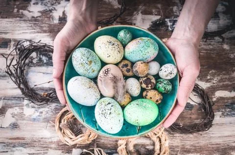 Easter composition. Female hands holding a plate with colorful Easter eggs. Stock Photos