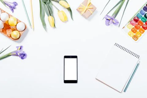 Easter composition: flowers, mobile phone, painted eggs, watercolors and a .. Stock Photos