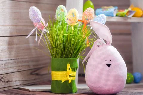 Easter composition. Funny creature, Easter eggs, green grass on a wooden Stock Photos