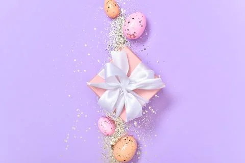 Easter composition with a gift and Easter eggs on a purple background Stock Photos