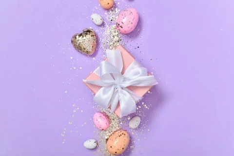 Easter composition with a gift and Easter eggs on a purple background Stock Photos