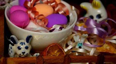 Easter composition with painted chicken eggs in a white plate, colored ribbons,  Stock-Fotos